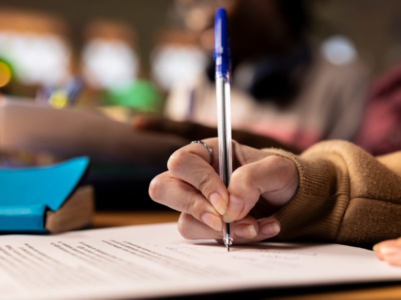 Team of college students working on a project related to business management, taking notes from reliable sources and other materials in the library. Brainstorming entrepreneurship ideas. Close up.